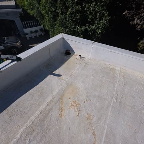 A flat roof half cleaned, the washed section white and the rest still streaked
