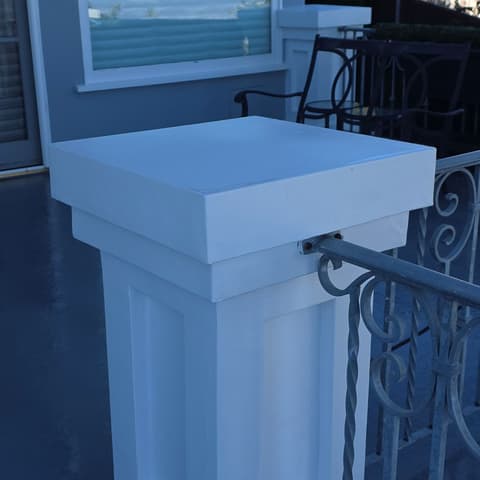 A white balcony pillar washed clean beside a wrought-iron rail