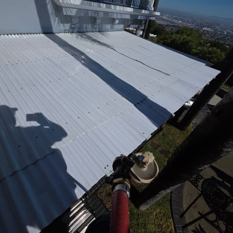 The corrugated awning after pressure washing, bright white with the city spread out below