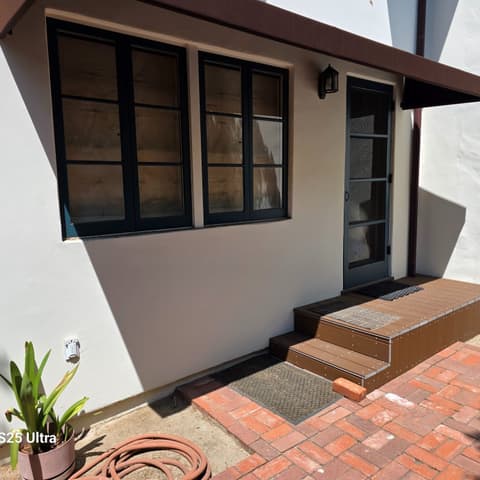 Black-framed windows on a white wall above a brick step, cleaned and streak-free