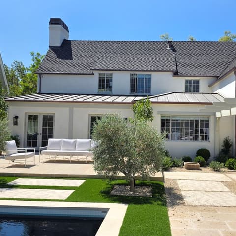 A white two-storey house seen from the pool terrace with every window cleaned